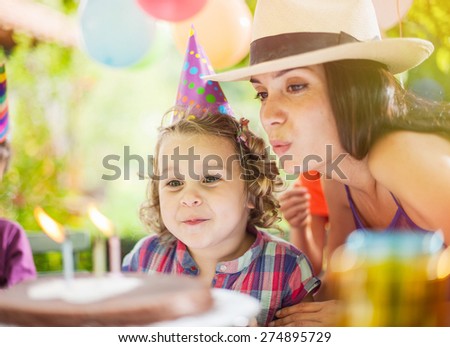 Garden party for the daughter \'s birthday, with mum, Girl makes a wish and blows her candles