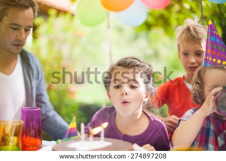 Birthday party in family. Girl blowing candles with her siblings