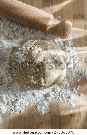 Top view, cake dough, flour and rolling pin on a wooden board