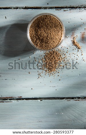 coriander powder in a bowl on wooden background