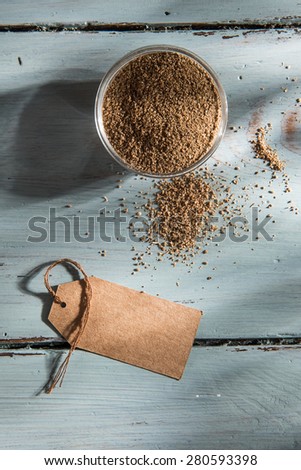 coriander powder in a bowl with a blank label, on wooden background