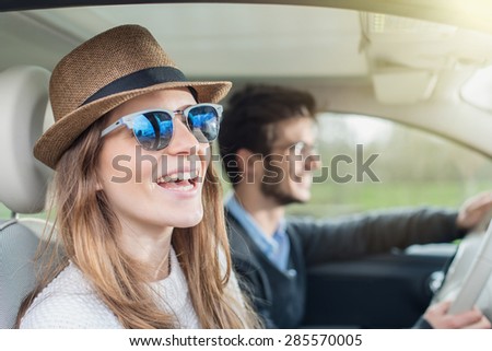 Young couple in his car, happy to drive on a country road, focus on the woman