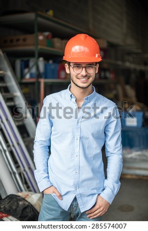 looking at camera, a young man with a helmet on his head on an industrial site