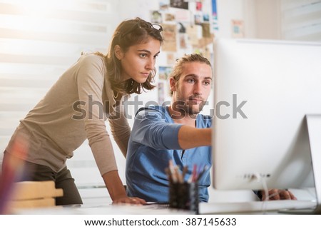 Two young colleagues working on a project on computer