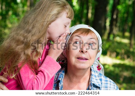 girl whispers to her grandmother\'s ear