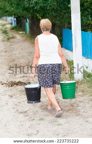 man carries two buckets of water