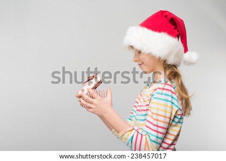 Portrait of happy little girl in santa hat with gift box over white background