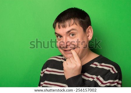 Funny young man is wondering while he pulling his lip downwards with finger