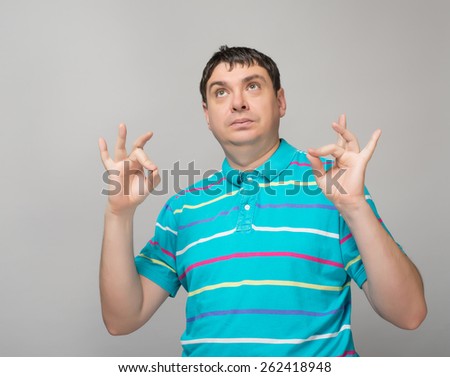 Gesturing OK sign. Cheerful young man   gesturing OK sign while standing against grey background