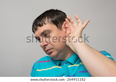 young man holding his hand near his ear, eavesdropping