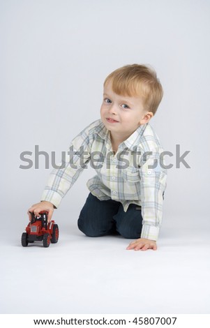 Boy plaies with toy - car,on egg white background.