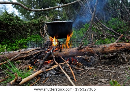 Cooking in the mountains. Cauldron on fire