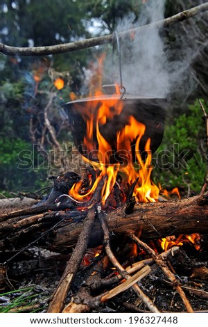 Cooking in the mountains. Cauldron on fire