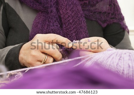 Old womans hands knitting a scarf with purple wool
