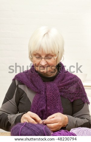 Portrait of happy old woman knitting with wool and metal knitting needle