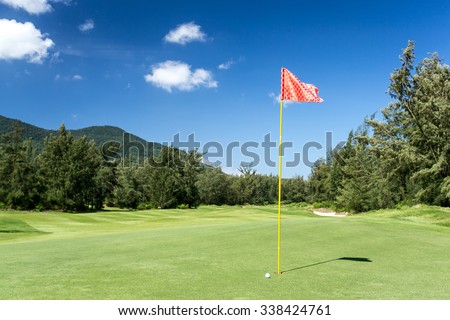 red Golf flag in hole and ball with blue sky