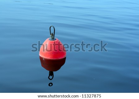 red-orange plastic buoy with iron loop on the blue water