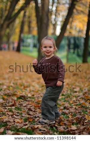 little beauty girl playing autumn yard with yellow leafs