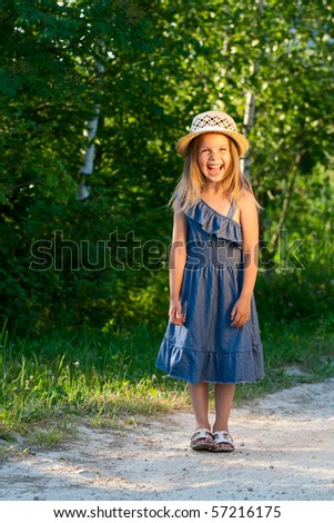 Laughing beautiful girl stand at the rural road in the jeans dress.