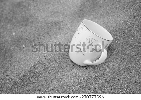 black & white concept for relaxation, coffee mug in sand