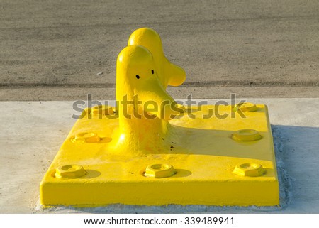 Bright yellow boat cleat for securing boats at the dock, with two eyes drawn on it to look like a bird