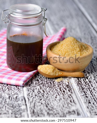 Brown cane sugar and honey on wooden board.