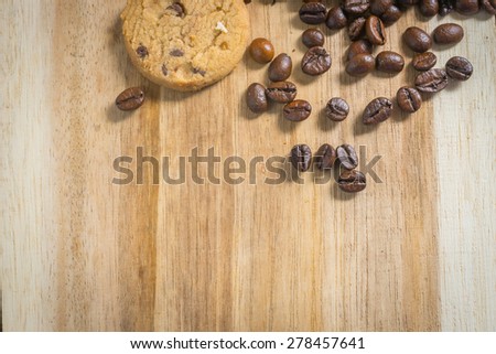 Coffee beans and chocolate chip cookies on a wooden table, warm tone style