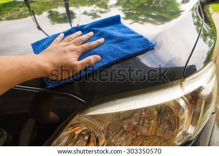 Close up man hand with blue microfiber cloth cleaning the car