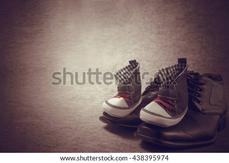 Daddy\'s boots and baby\'s sneakers, on wood background, fathers day concept.vintage color