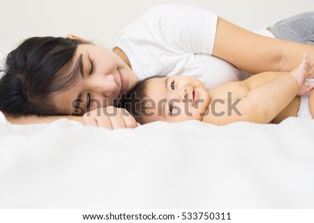 happy family.asian  mother playing with her baby in the bedroom.
