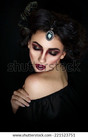 girl with art makeup and hairstyle in a half-turn touching her naked shoulder