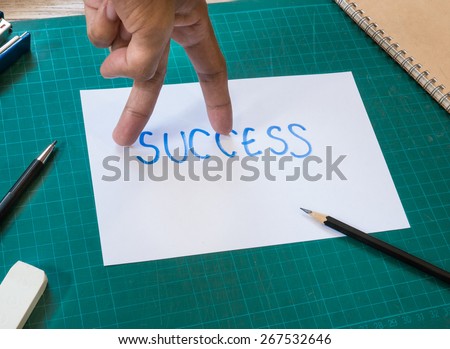 Forefinger and middle finger look like walking action on success text paper.