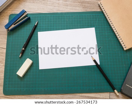 Stationery and blank white paper on cutting mat on wooden background ( White paper for text )