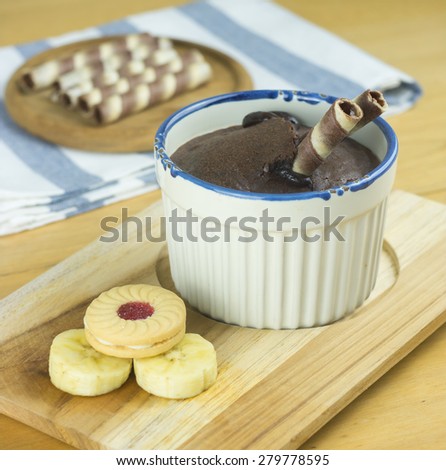 Chocolate fondant lava cake with cookies and banana in ceramic cup on wooden tray