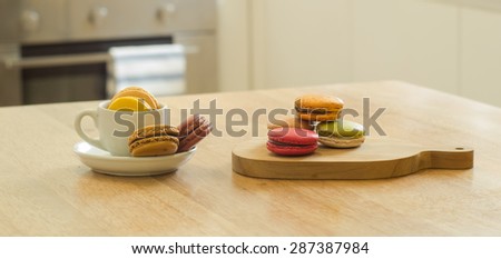 Colorful French macarons cookie in cup and wooden tray on wooden table in a kitchen