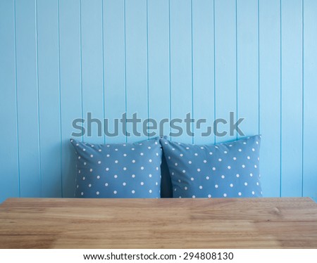 Blue wooden wall background with polka dot pillows and foreground is wooden table  (Composition and space for text)