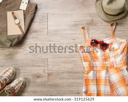 Top view of Women cloth and accessories -  Orange dress and red sunglasses , tote bag,  watch, notebook, hat  and shoe  on wooden background ( Composition and space for text )