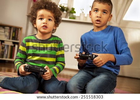 Mixed race boys playing video games at home.