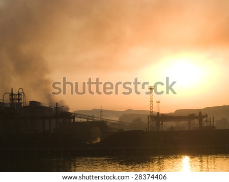 Smoking plant near a river at sunset