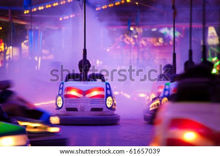 Bumper cars, People driving through artificial smoke. Motion blur