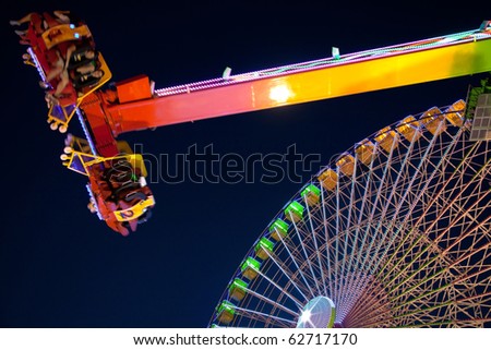 Ferris wheel and carnival ride at night. Motion blur