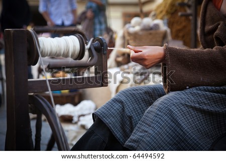 woman using an old spinning wheel to turn wool into yarn
