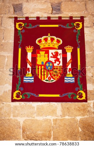 Coat of arms of The Spanish Crown in a tapestry hung on an ancient stone wall