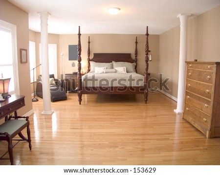 Spacious Master Bedroom with four-poster queen bed, wood floor, white ceiling and several windows.