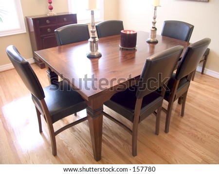 Dining Room with dark wood table, six chairs, candelabra and two windows with a natural wood floor.