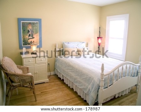 Bedroom with wood floor, white ceiling, window, red lamp, bedside table and throw pillows.
