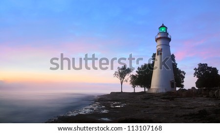 The Marblehead Lighthouse Radiates It\'s Green Light As The Sun Warms The Eastern Sky Initiating A Brand New Day At Marblehead Ohio On Lake Erie, USA