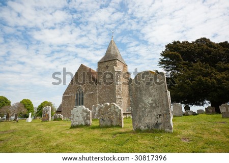 Old St. Clement\'s church and graveyard against blue sky with white clouds, Old Romney, Kent, UK