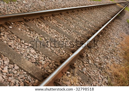 Two rusty rail tracks on gravel with some grass