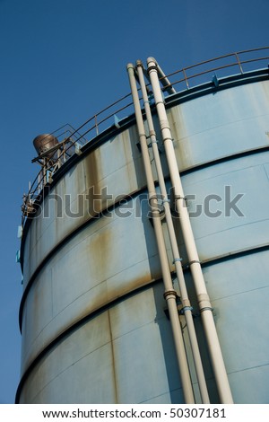 Blue and rusty industrial tank against a clear blue sky